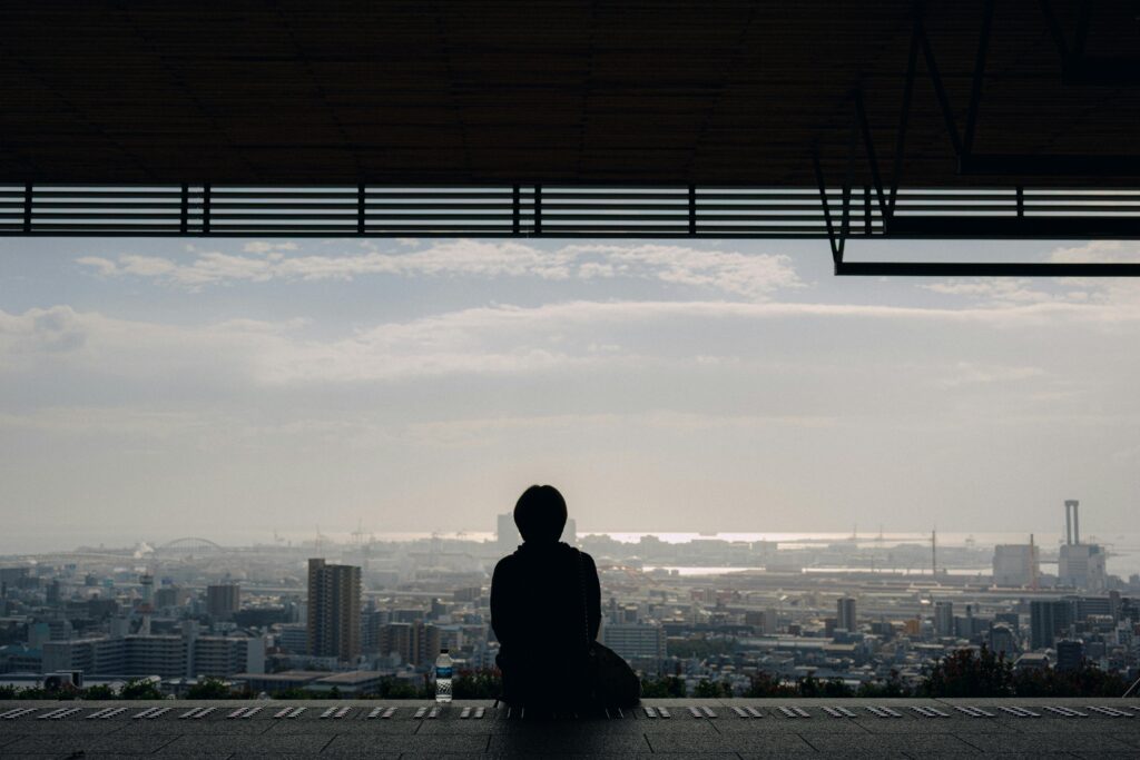 Person sitting alone with their thoughts overlooking a busy city