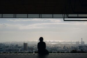 Person sitting alone with their thoughts overlooking a busy city